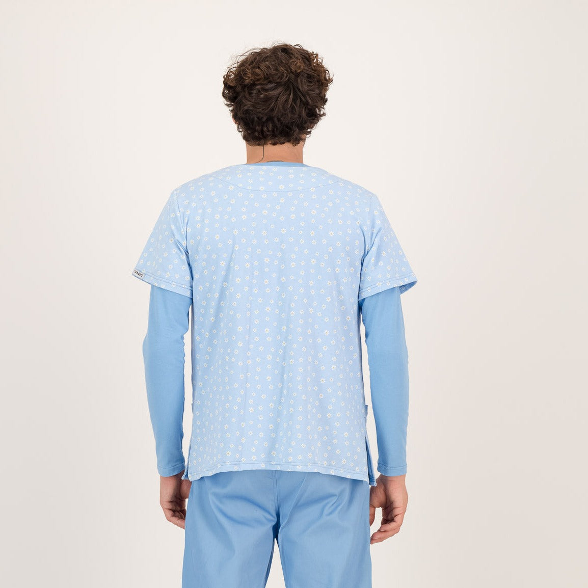 Male model showing the back of a baby blue floral scrub top